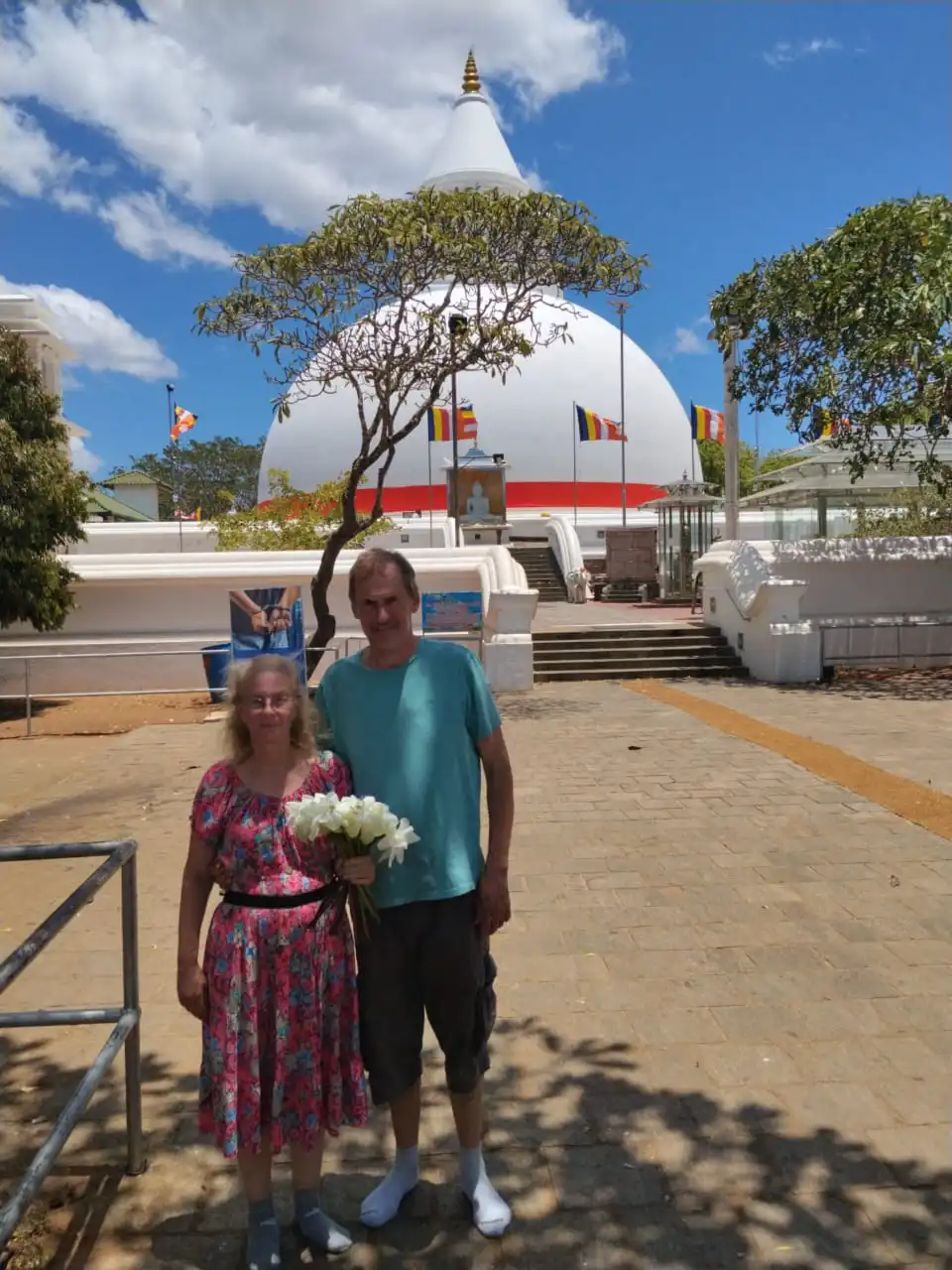 Couple presenting white lotus flowers before the sacred ancient stupa